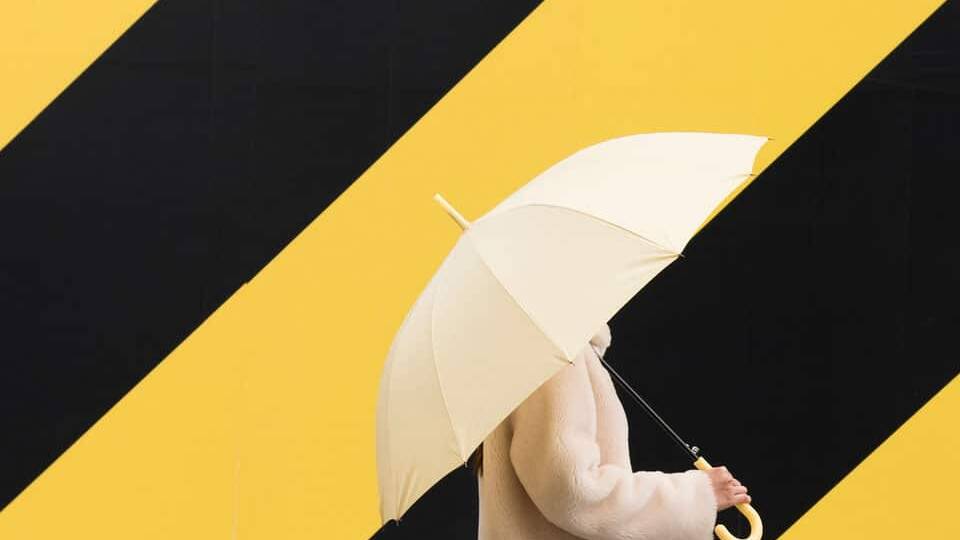 woman with umbrella in front of yellow and black striped wall